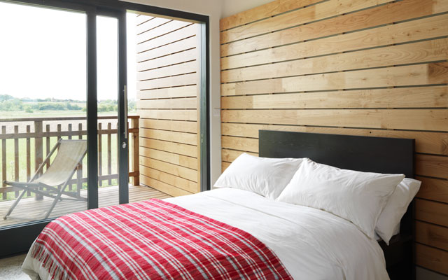 Timber-clad bedroom with sliding glazed doors leading to a small terrace