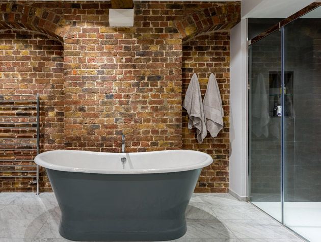 bathroom in a warehouse conversion with exposed brick, freestanding bath and modern shower space