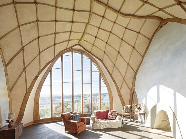 Room with high ceiling and floor to ceiling windows, sofa and armchair in the Grand Designs Herefordshire house