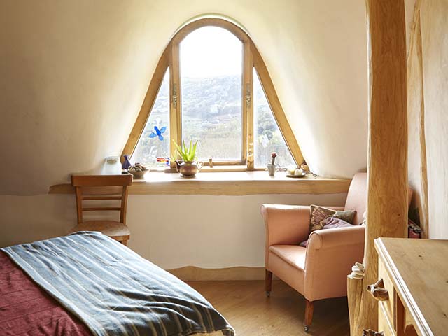 Bedroom with armchair, desk and fairy window