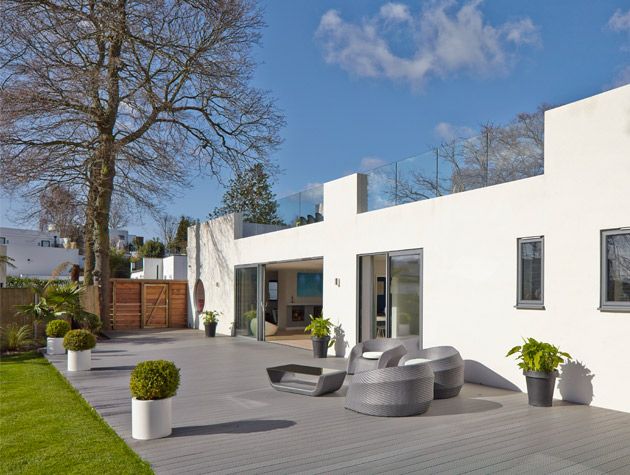 White house with back garden with grey patio, rattan furniture, potted plants and lawn -la-hally-architects-home-improvements-granddesignsmagazine.com
