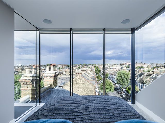 Loft conversion bedroom with large glass windows -uv-architects-granddesignsmagazine.com