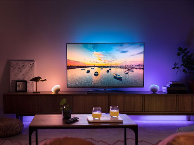 A living room with a large smart TV, coffee table and lit with Philips Hue smart lighting -meet-hue-home-improvements-granddesignsmagazine.com