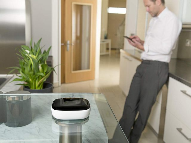 man at home in kitchen using Panasonic smart home security system