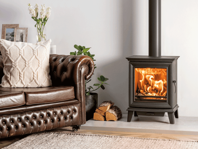 A wood burning stove next to a Chesterfield sofa
