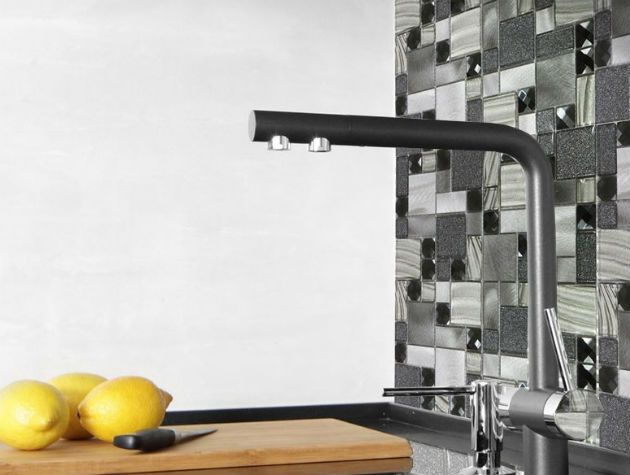Grey wall tiles in a kitchen with taps faucet and lemons on chopping board copy