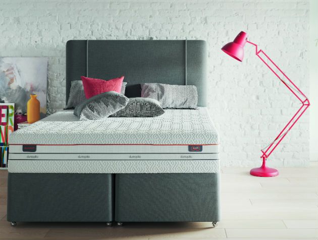 modern bedroom with undressed bed and large anglepoise lamp