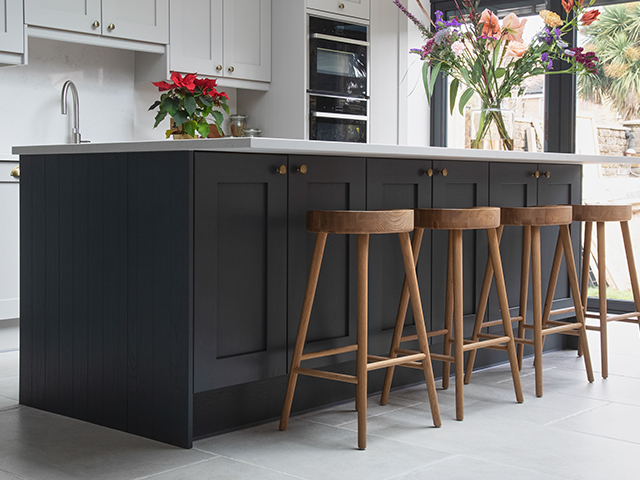 a dark grey kitchen island with natural stone flooring - home improvements - granddesignsmagazine.com