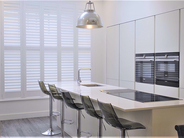 modern white gloss kitchen with seating and shuttered windows - grand designs