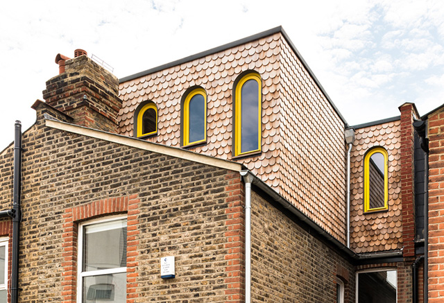exterior of quirky house with cladding and arch yellow frame window - grand designs - home improvements 