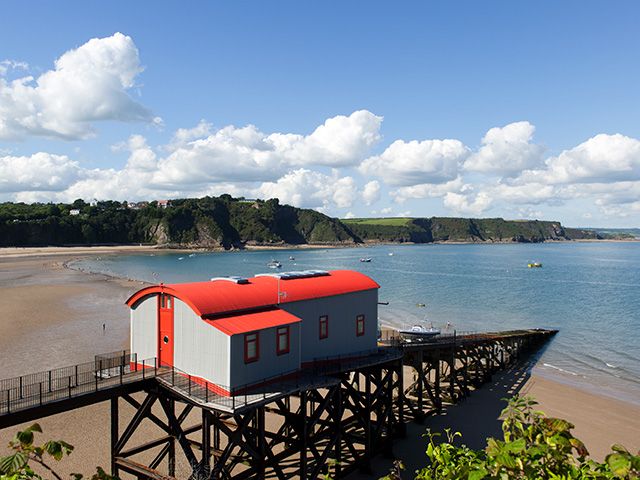 Lifeboat house on wooden pier overlooking South Wales beach and stunning mountains