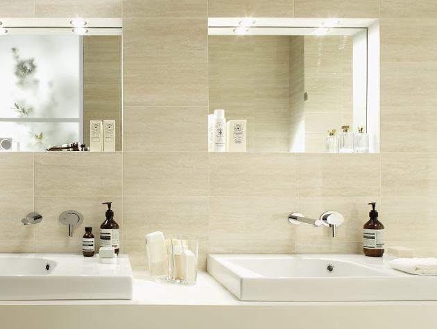 two bathroom sinks with illuminated mirrors and wall tiles