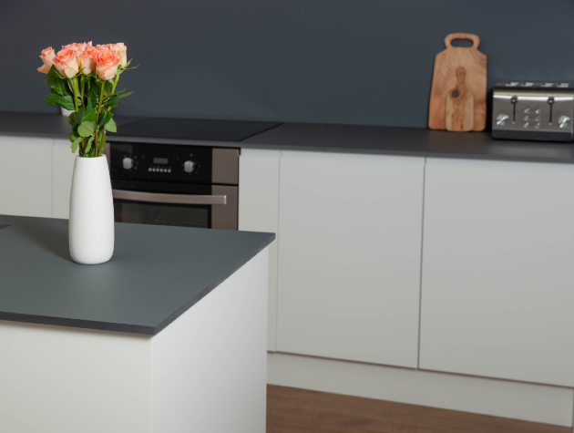 kitchen with grey worktop white cabinets and flowers