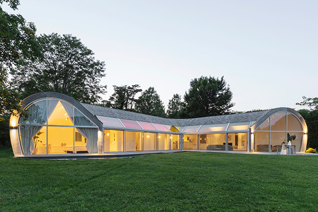 A expansively glazed single-storey house deign with curved walls and roof