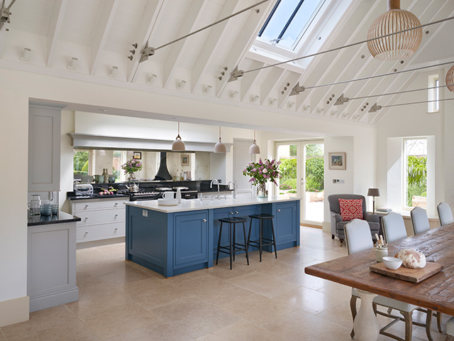 A kitchen in a barn conversion showing a blue island unit in an otherwise white painted scheme.