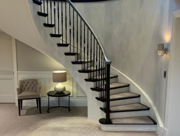 Modern staircase with black hand rail table and chair