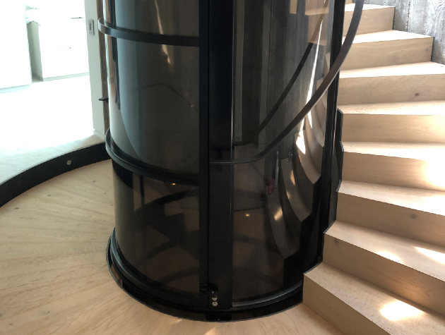 black curved lift with stairs winding around it