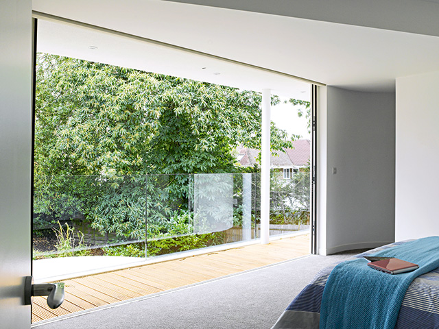 Bedroom with carpet and full lebgth window overlooking trees outside