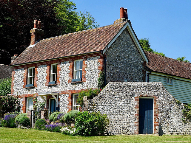 Period home with flint clad exterior and red tiled roof.