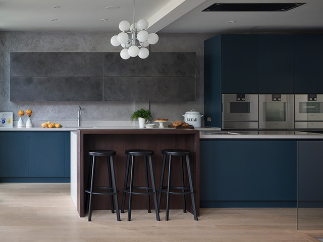 Dark blue fitted kitchen with large island including a breakfast bar with barstool seating at one end