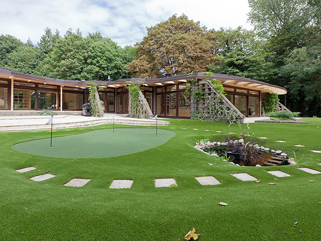 A putting green stands in the garden of the single-storey house in the grounds of a medieval monastery