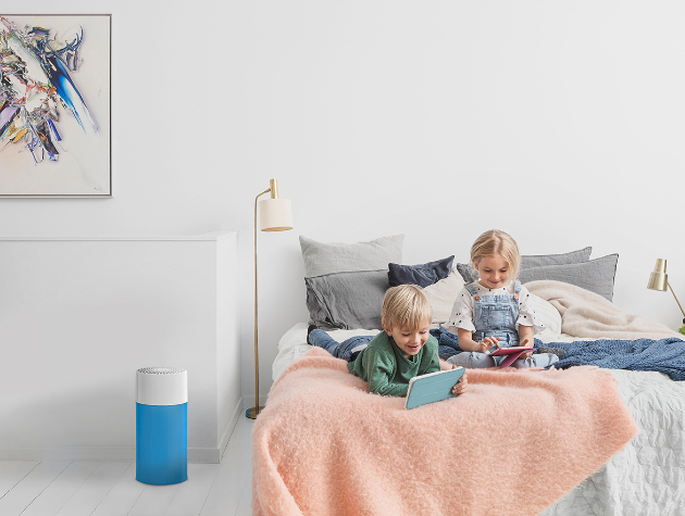 two children playing with tablets on a bed