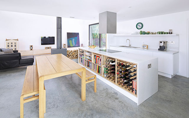 An open-plan kitchen with white units and a dining area in front of a central island