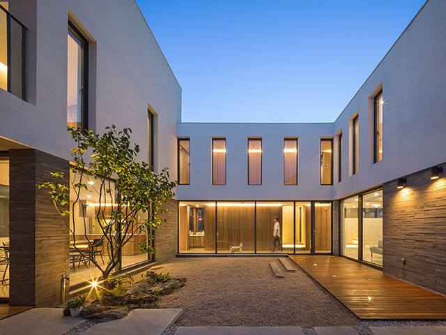 A gravel garden with a small tree in the internal courtyard of this best self build home in Korea