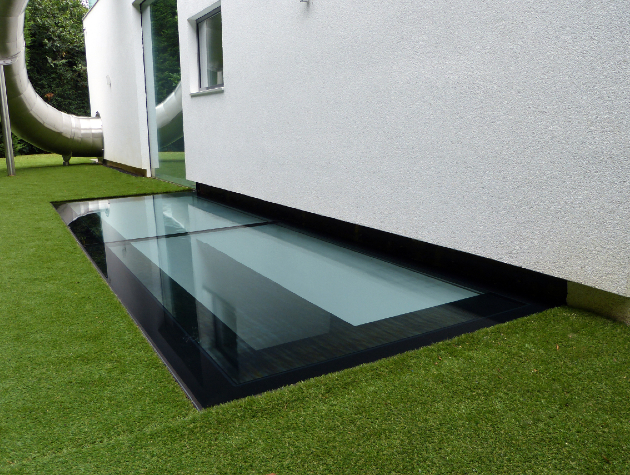 artificial grass with glazed floor panel next to wall