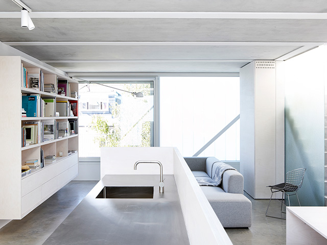 The minimalist interiors in the kitchen and living room, with bookshelves and minimal clutter on surfaces