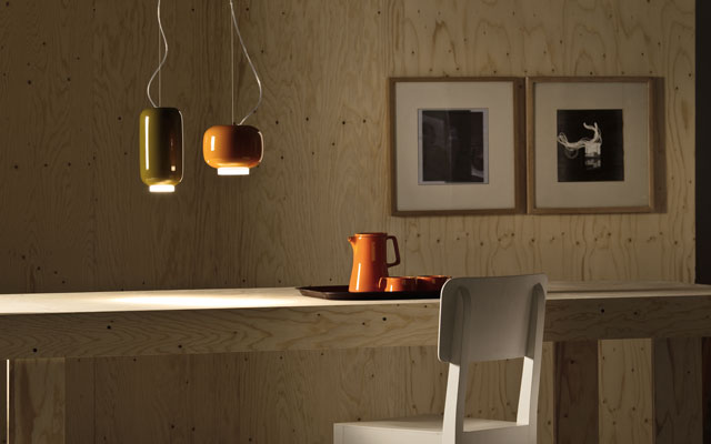 Two pendant lights, one orange and one grey, hanging above a dining table