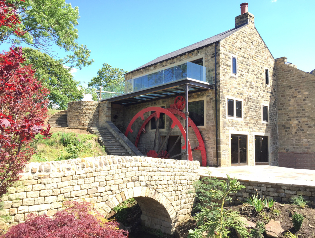 converted stone mill house with wheel and bridge