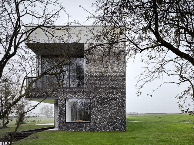 Exterior of the flint studded Flint House looking at the gable end with cantilever first floor with balcony