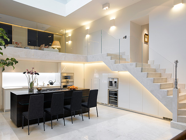White marble kitchen with black island unit in the centre. Another Grand Designs most expensive home.