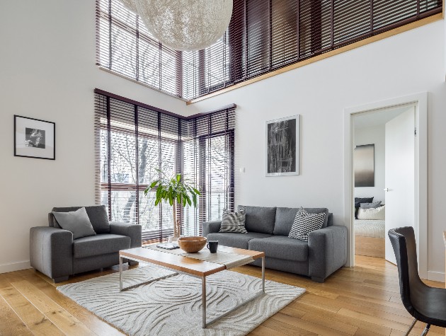 living room with grey sofas wooden tables and blinds on windows