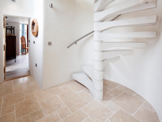 room with tiled floor and spiral staircase in white concrete