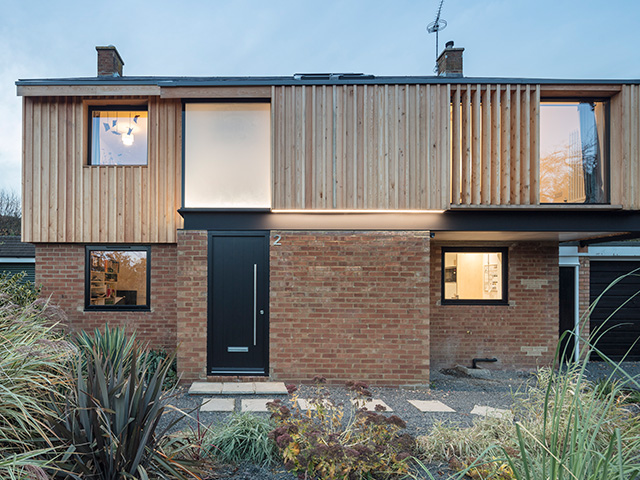 Brick and timber clad home exterior with black energy efficient front door with steel bar handle