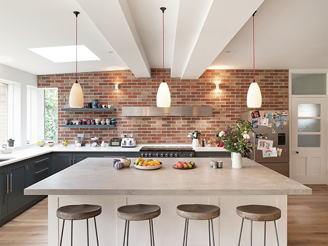 Three pendant lights hanging above a kitchen island unit with bar stools in front