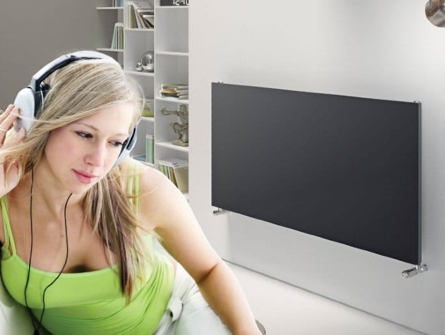 woman with headphones on in living room next to modern radiator