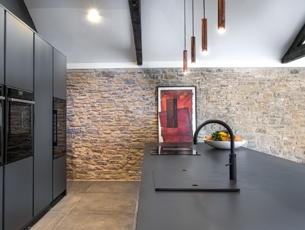 grey kitchen island and cabinets with stone wall