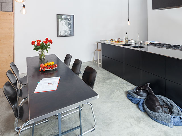 Kitchen/diner with six seater fold up black metal dining table accessorised with a vibrant bouquet and kitchen island worktop