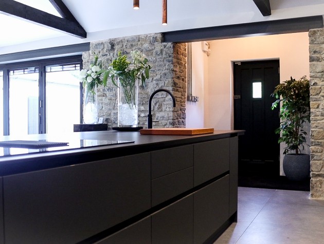 kitchen island with sink and tap stone wall and patio doors behind