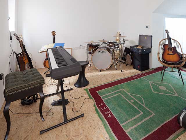 Music room with keyboard, guitar, drum kit and football mat