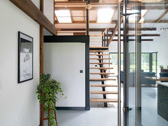 Inside house showing wooden floating stairs, white aesthetic and foilage of Grand Designs Sevenoaks Barn conversion
