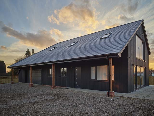 The exterior of a Dutch barn with brick pillars and black tiled roof