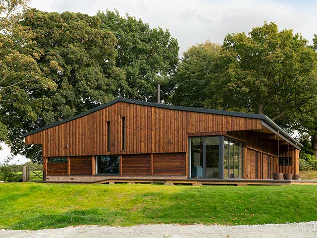 Grand Designs Sevenoaks barn conversion exterior surrounded by trees and green grass