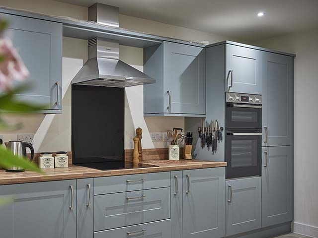 Duck egg blue kitchen units and wooden surfaces with built in oven