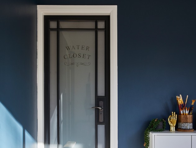 room with glass and black framed door marked water closet
