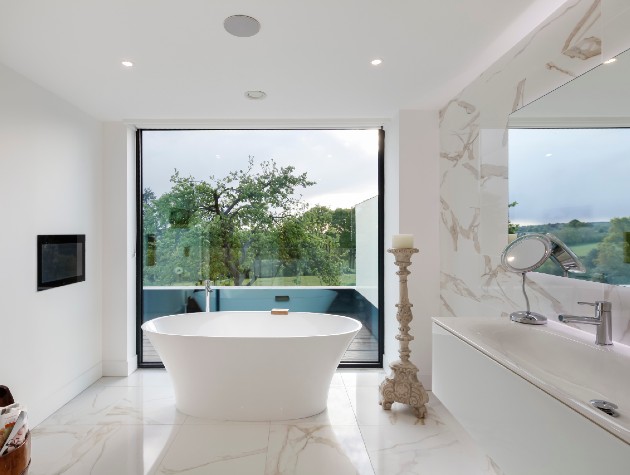 white bathroom with freestanding bath next to sliding door and balcony