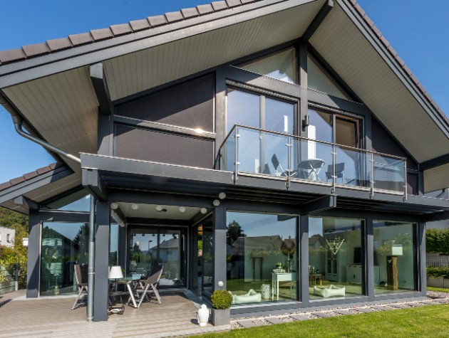 Modern post and beam black timber frame eco home with pitched roof and glass balcony